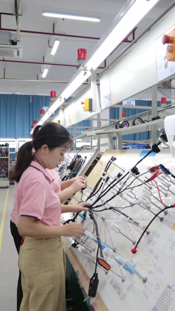 Nexharn assembly worker performing detailed wire harness inspection and quality control